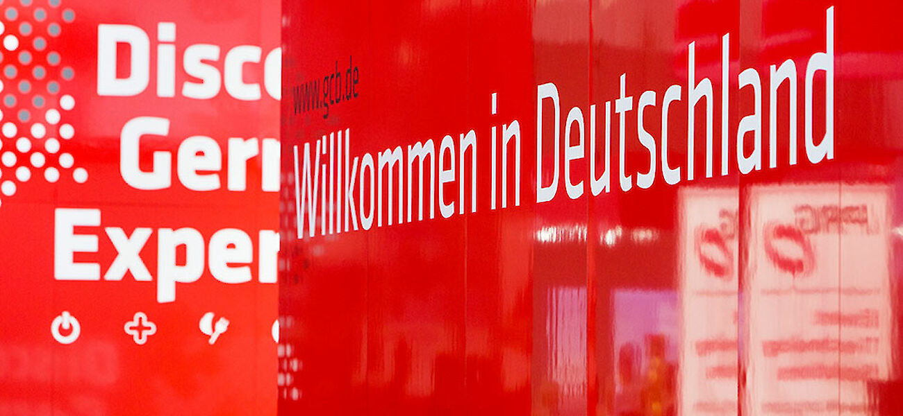 Schriftzug "Willkommen in Deutschland" auf rotem Messestand-Element des GCB