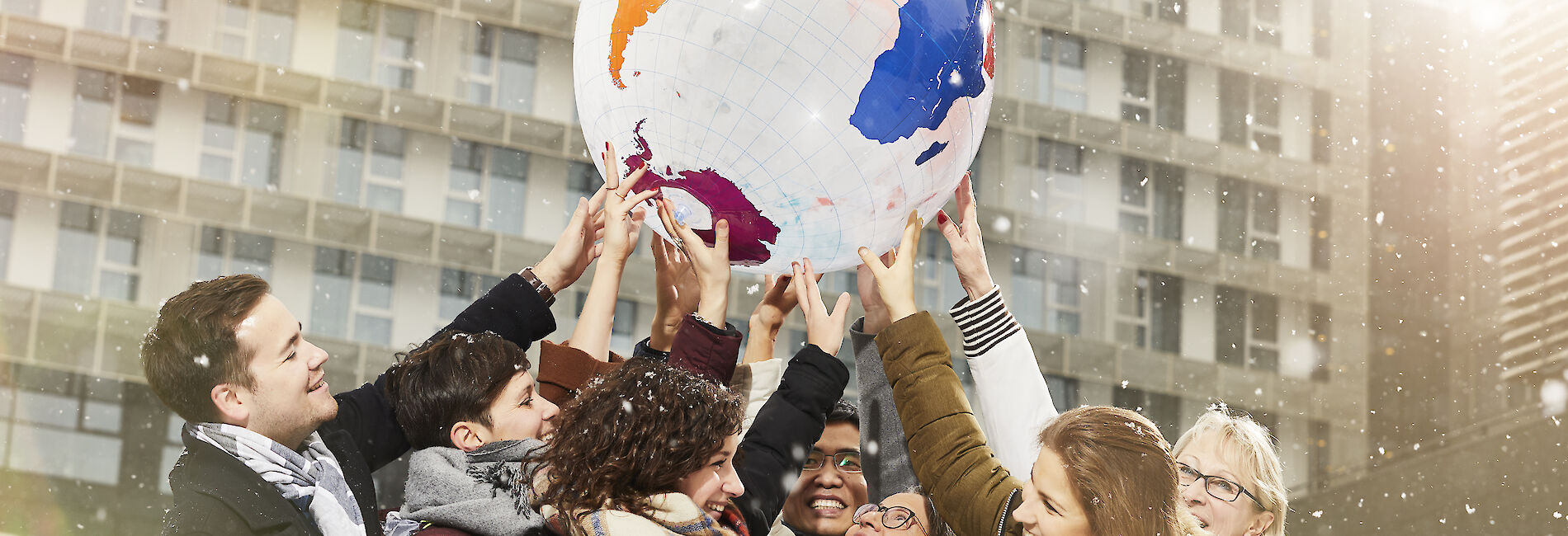 Mitglieder des Team GCB halten gemeinsam einen Kunststoff-Globus in die Luft