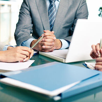 Three people in business outfits at a table with documents