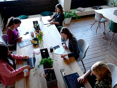Fünf Frauen arbeiten gemeinsam an einem langen Tisch