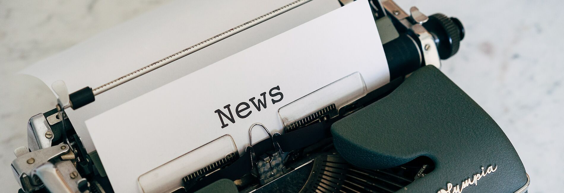 Schreibmaschine der Marke Olympia mit beschriebenem Blatt "News"
