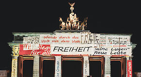 Brandenburger Tor mit Projektion von verschiedenen Schriftzügen zum Thema Freiheit und Wiedervereinigung.
