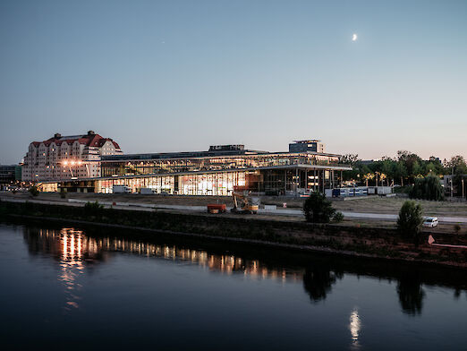 Blick über die Elbe auf das beleuchtete Congress Center bei Nacht.