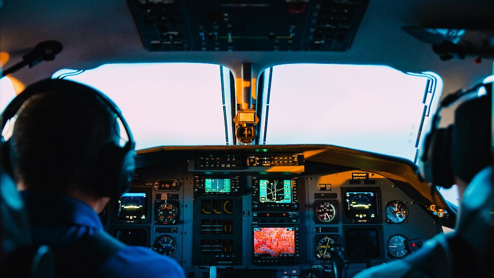 Blick über die Schulter auf zwei Piloten im Cockpit