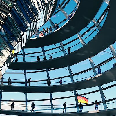 Die gläserne Kuppel des Deutschen Bundestags ist von innen zu sehen, durch eines der Fenster sieht man die deutsche Flagge