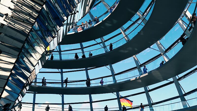 Die gläserne Kuppel des Deutschen Bundestags ist von innen zu sehen, durch eines der Fenster sieht man die deutsche Flagge