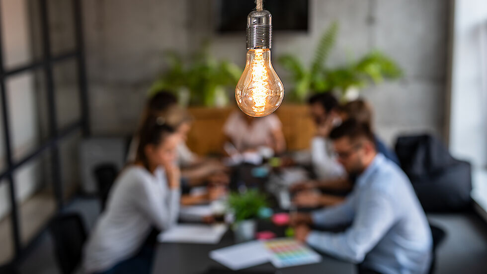 Light bulb and people sitting at a table working together