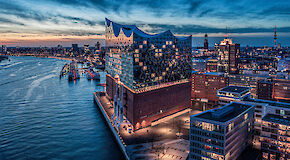 Elbphilharmonie on the river Alster in Hamburg at sunset, windows illuminated in a heart shaped symbol.