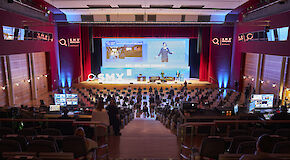 Audience of SMX in a large conference room looking towards the stage with a female speaker giving a presentation.