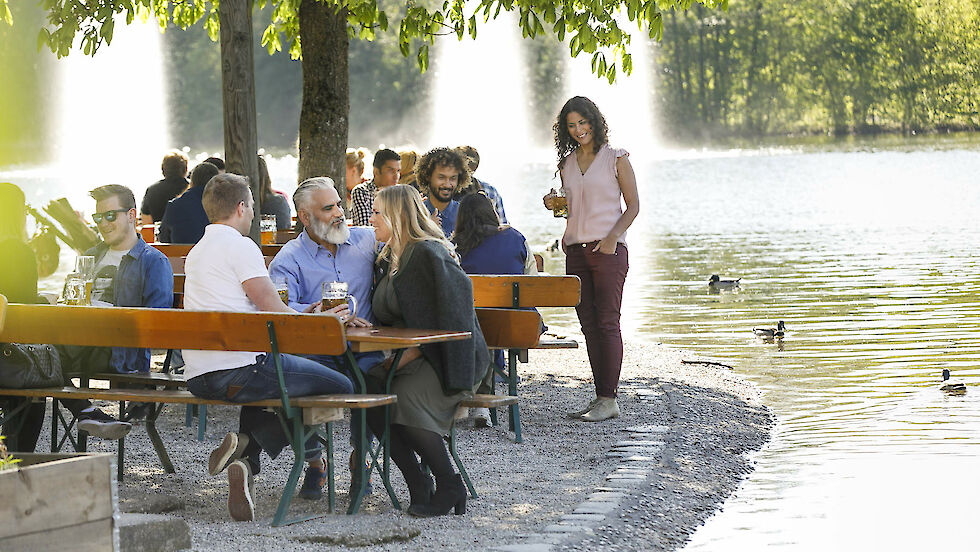 people sitting in Bavarian beer garden next to water