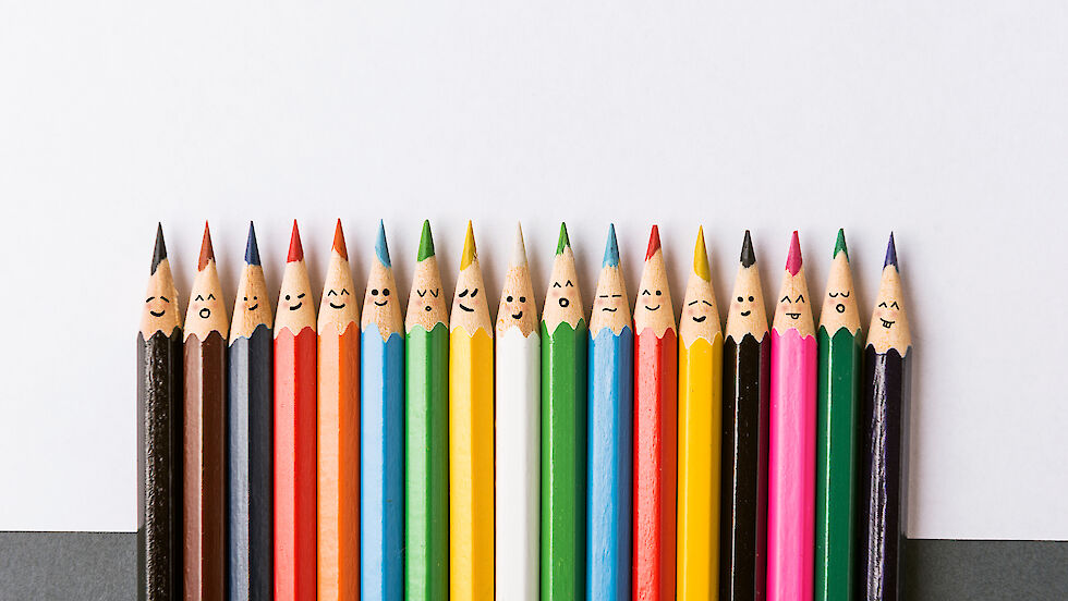 Crayons with painted faces in a row
