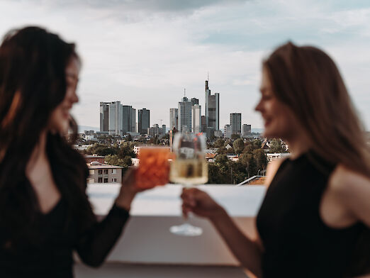 Zwei Frauen mit Gläsern vor Frankfurter Skyline