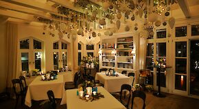 Weihnachtlich geschmückter Raum mit drei gedeckten Tischen